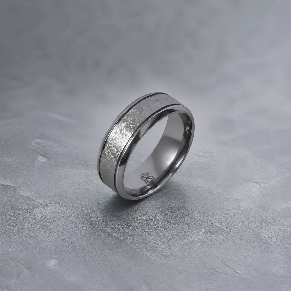 Bague Ravenstone en tantale brossé, posée sur un fond gris texturé.