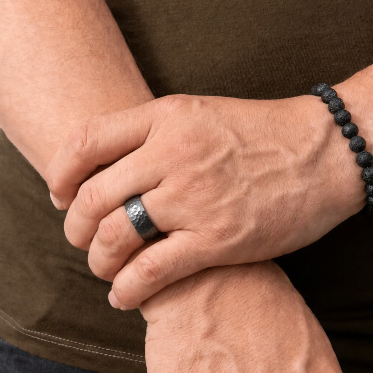 Bague Ravenstone en zirconium noir martelé, portée aux mains dans une scène sobre.