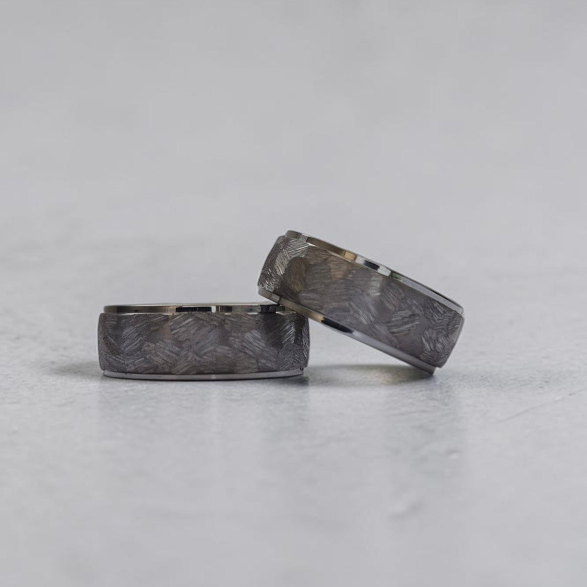 Duo de bagues Ravenstone en tantale gris à texture brossée, illustrant les finitions techniques des alliances homme.