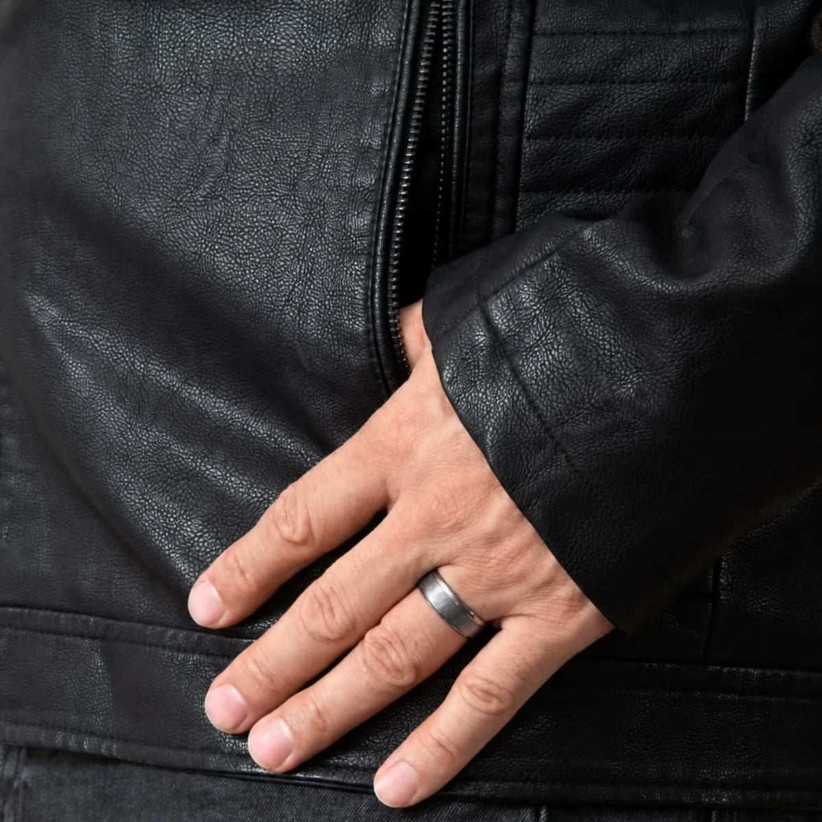 Bague Ravenstone en tantale brossé, portée à la main d'un mannequin portant une veste en cuir noir.