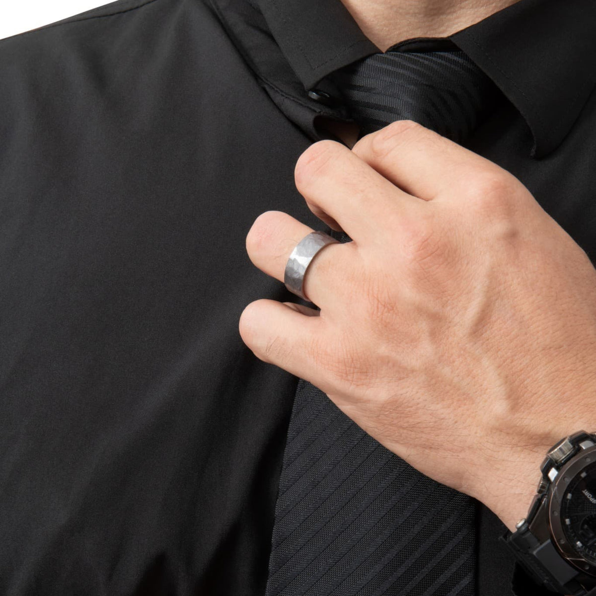 Bague Ravenstone en tantale gris brossé avec intérieur en or rose poli, portée à la main dans une scène sombre et élégante.