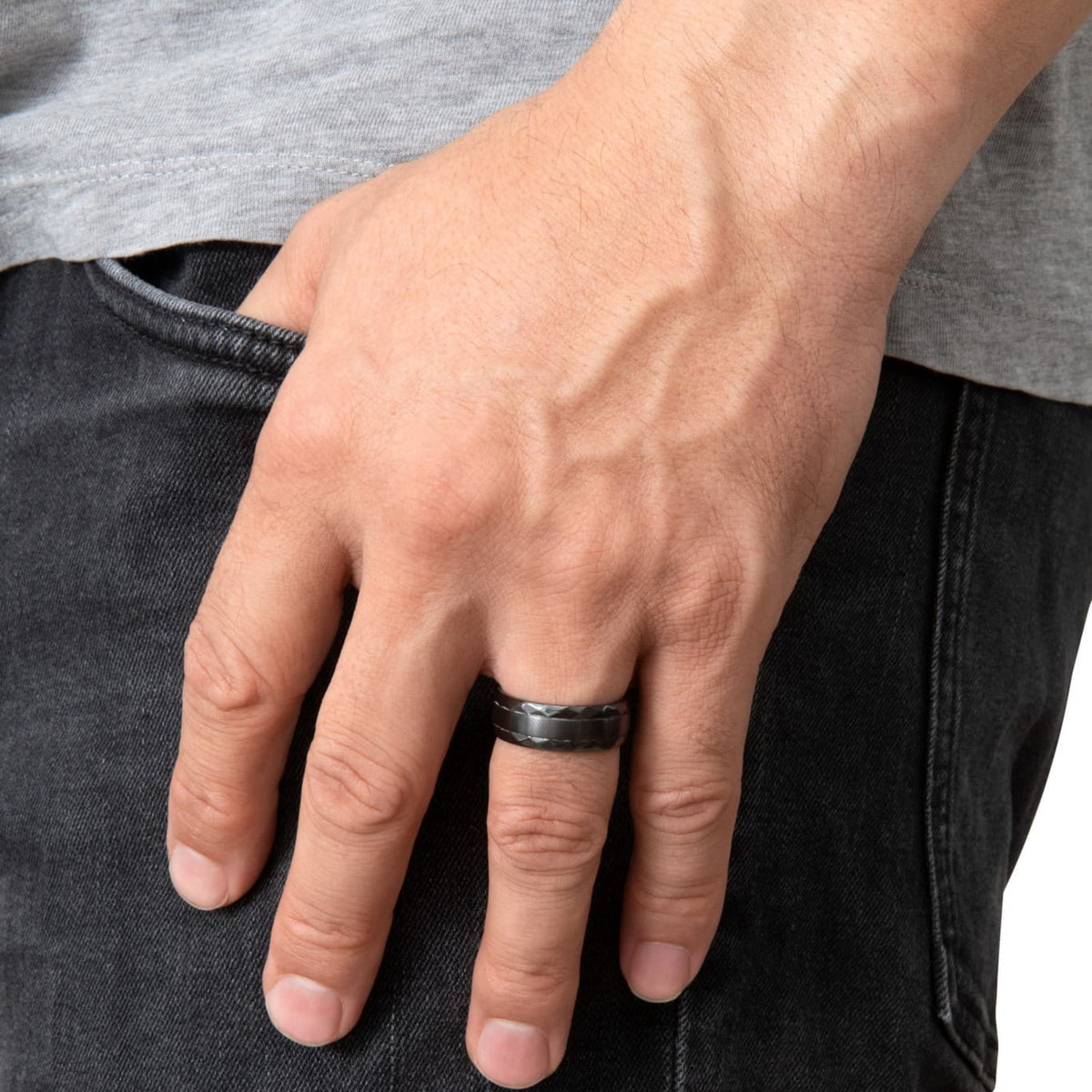 Bague Ravenstone en zirconium noir avec bande lisse et bords facettés, portée à la main près d’un jean sombre.