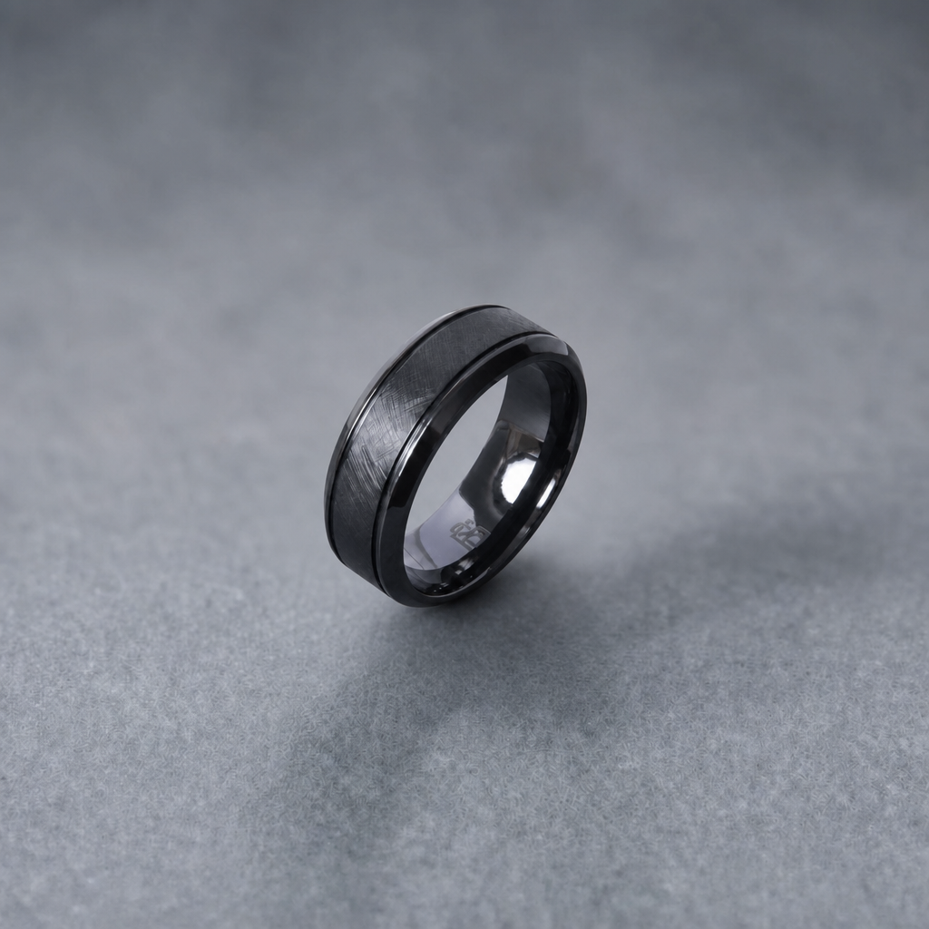 Bague Ravenstone en zirconium noir à finition brossée, posée sur un fond gris lisse.